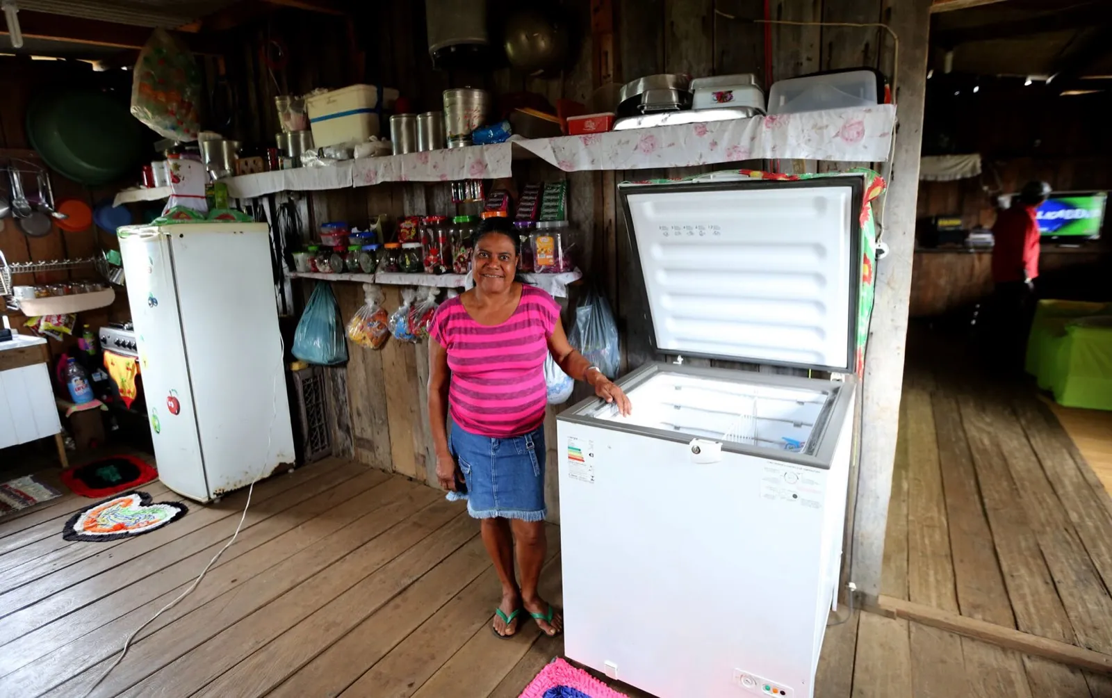 Moradora de assentamento no Acre ao lado de freezer e geladeira em casa atendida pelo Luz para Todos.