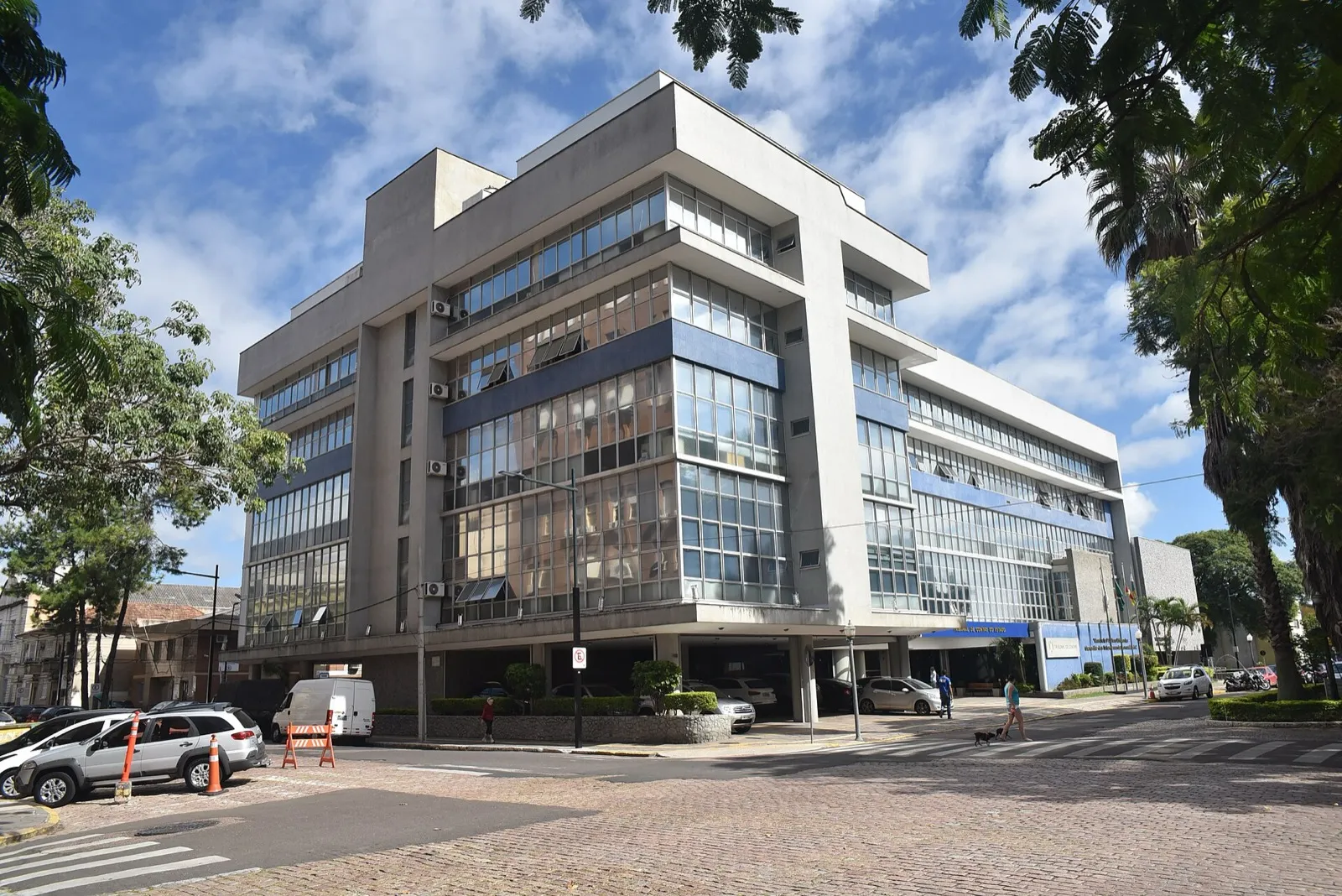 Fachada do prédio-sede do Tribunal de Contas do Estado do Rio Grande do Sul, de concreto e vidro, com faixa azul na entrada.
