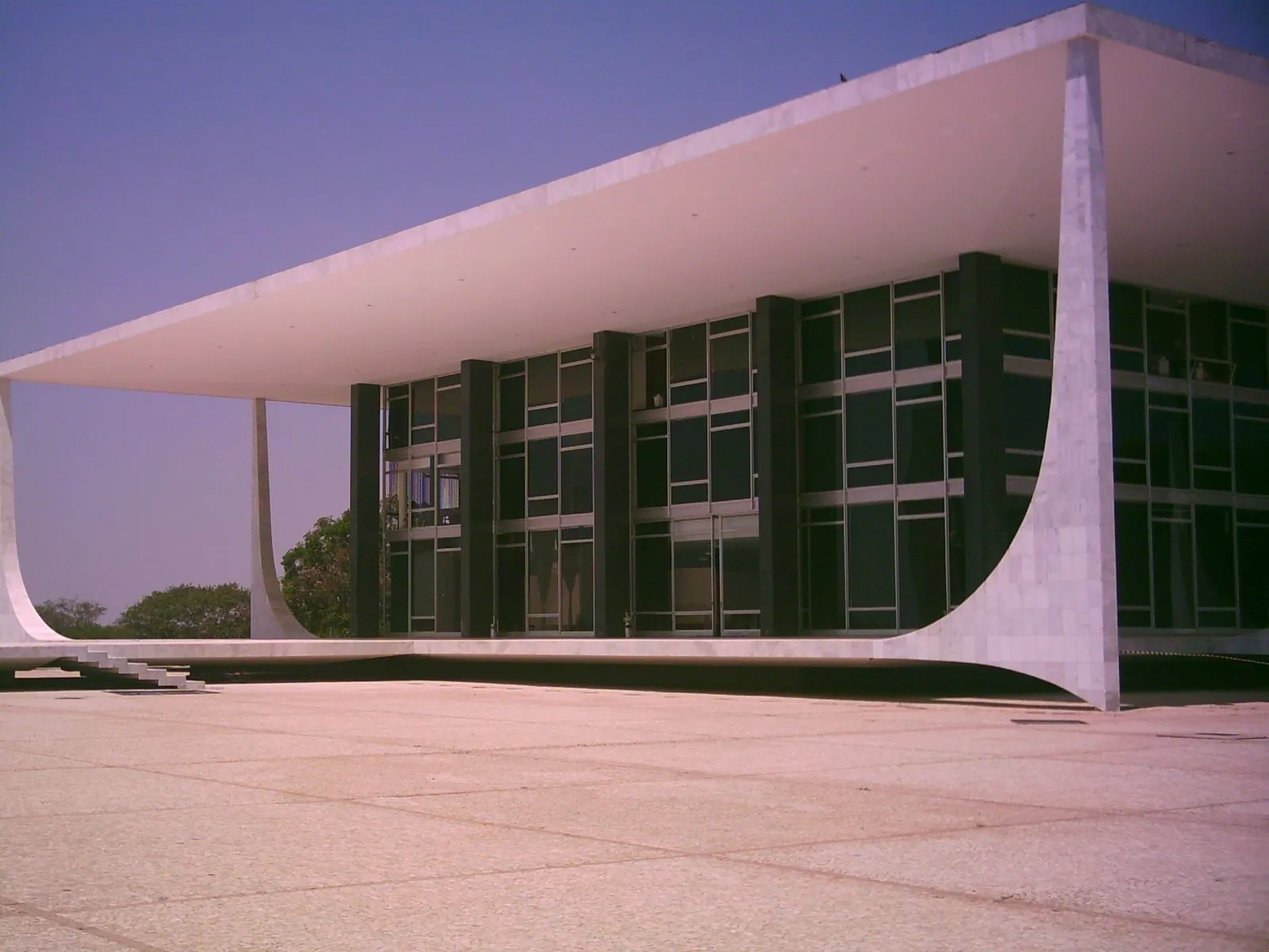 Fachada do prédio do Supremo Tribunal Federal, com pilares brancos curvos e vidraças escuras, sob céu azul, em Brasília.