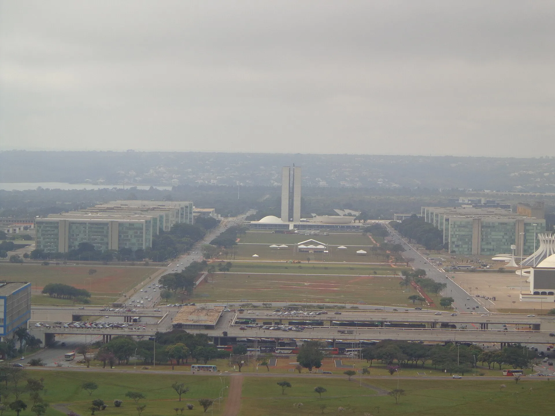 Vista aérea da Esplanada dos Ministérios, em Brasília, com prédios de ministérios dos dois lados e o Congresso Nacional ao centro.