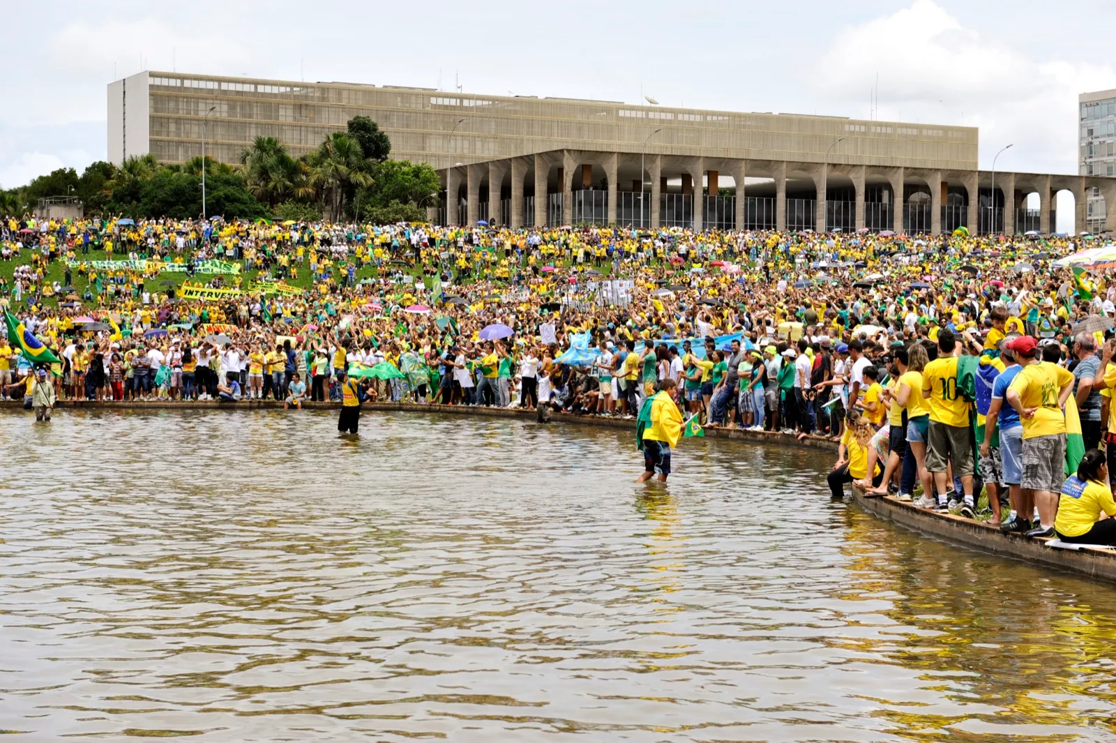 Milhares de manifestantes vestidos de verde e amarelo ocupam o gramado e o espelho d'água em frente ao Congresso Nacional, em Brasília.