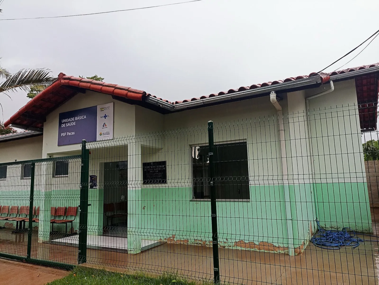 Fachada de Unidade Básica de Saúde, com placa do SUS e da Saúde da Família, em dia nublado.