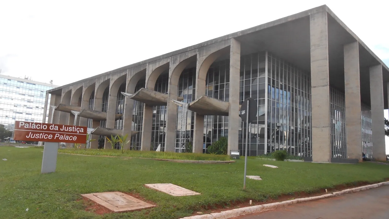 O Palácio da Justiça, prédio de concreto com arcos na fachada e placa com o nome em português e inglês, em Brasília.