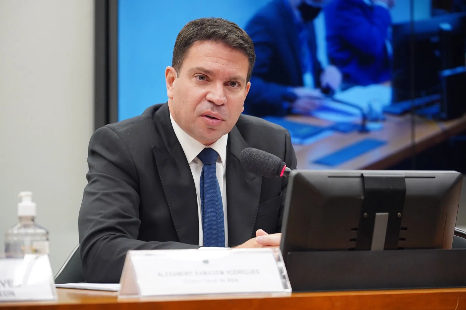 Alexandre Ramagem, de terno escuro e gravata azul, fala ao microfone sentado à mesa de uma audiência na Câmara dos Deputados.
